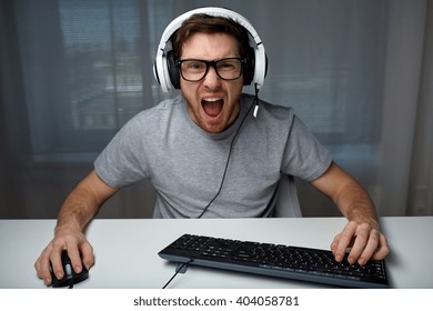 Technology, Gaming, Entertainment, Let's Play And People Concept - Angry Screaming Young Man In Headset With Pc Computer Playing Game At Home And Streaming Playthrough Or Walkthrough Video