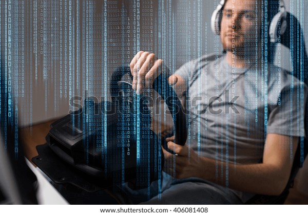 technology, gaming,\
entertainment, let\'s play and people concept - close up of young\
man in headphones with pc computer playing car racing video game at\
home and steering\
wheel