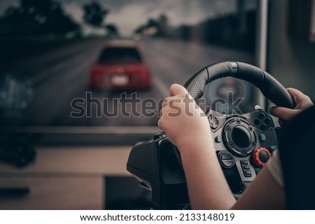 Technology, gaming, entertainment and people concept - young man playing car racing video game at home and steering wheel.