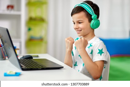 technology, gaming and people concept - boy in headphones celebrating victory in video game on laptop computer at home - Powered by Shutterstock