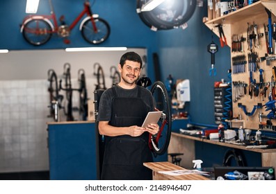 Technology has its place, even in bicycle repair. Shot of a man using a digital tablet in a bicycle repair shop. - Powered by Shutterstock