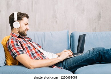 Technology, Home, Music And Lifestyle Concept - Smiling Man With Laptop And Headphones At Home