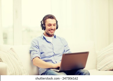 Technology, Home, Music And Lifestyle Concept - Smiling Man With Laptop And Headphones At Home