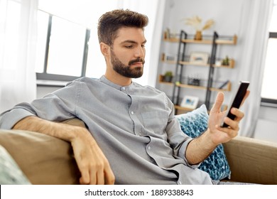 Technology, Internet, Communication And People Concept - Young Man Texting On Smartphone At Home