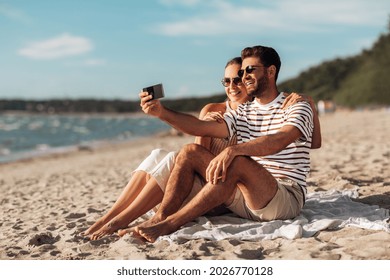tecnología, ocio y concepto de la gente - pareja feliz tomando selfie por teléfono inteligente en la playa de verano