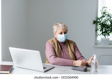 Technology, Old Age And People Concept - Lonely Sad Older Senior Woman In Face Medical Mask Working And Making A Video Call With Laptop Computer At Home During Coronavirus COVID19 Pandemic. Stay Home