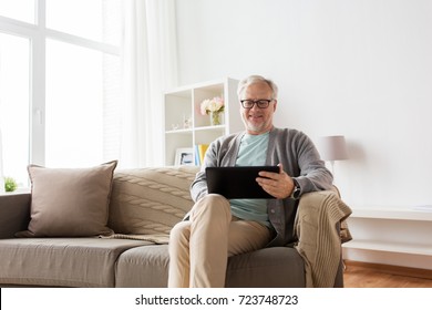 Technology, Old Age, People And Lifestyle Concept - Happy Smiling Senior Man With Tablet Pc Computer Sitting On Sofa At Home