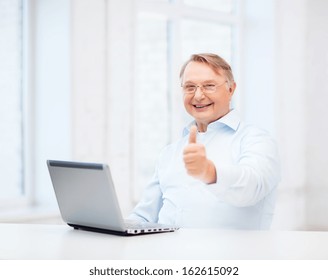 Technology, Oldness And Lifestyle Concept - Old Man In Eyeglasses With Laptop Computer At Home Showing Thumbs Up