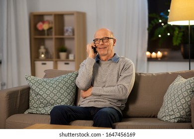 technology, people and communication concept - happy smiling senior man calling on smartphone at home in evening - Powered by Shutterstock