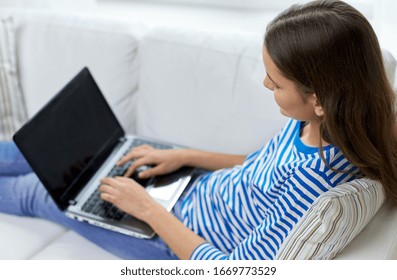 technology and people concept - close up of teenage girl typing on laptop at home