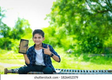 Technology And People Concept - Smiling Teenage Boy In Blue Shirt Showing Smartphone With Blank Screen