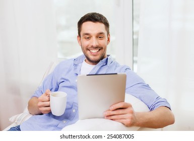 Technology, People And Leisure Concept - Handsome Man With Tablet Pc Computer And Cup Drinking Coffee Or Tea At Home