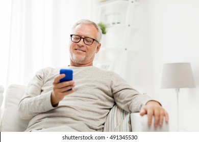 Technology, People, Lifestyle And Communication Concept - Happy Senior Man Dialing Phone Number And Texting On Smartphone At Home