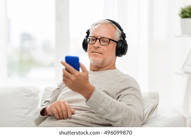 Technology, People, Lifestyle And Distance Learning Concept - Happy Senior Man With Smartphone And Headphones Listening To Music And Singing At Home