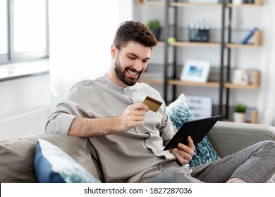 tecnología, personas y concepto de compras en línea - hombre sonriente feliz con tablet pc computadora y tarjeta de crédito en casa