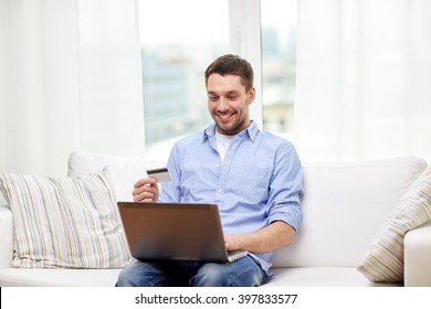 Technology, People And Online Shopping Concept - Smiling Man With Laptop And Credit Card At Home