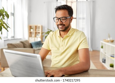 technology, remote job and lifestyle concept - happy indian man in glasses with laptop computer working at home office - Shutterstock ID 1740217295