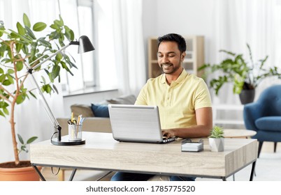 Technology, Remote Job And Lifestyle Concept - Happy Smiling Indian Man With Laptop Computer Working At Home Office