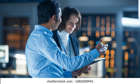 In Technology Research Facility: Female Project Manager Talks With Chief Engineer, they Consult Tablet Computer. Team of Industrial Engineers, Developers Work on Engine Design Using Computers - Shutterstock ID 1682600941