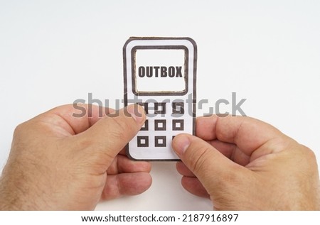 Technology and security concept. On a white background, in the hands of a person, a cardboard model of a telephone with an inscription on the screen - OUTBOX