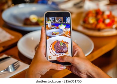 Technology and social network in people life. Woman holds phone and makes photos for social media before eating luxury fine food. Food photography or blogger - Powered by Shutterstock