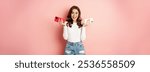 Technology, spring promo concept. Stylish glamour woman holding two smartphones, mobile phones in both hands, smiling pleased, buying new cellphone, pink background.