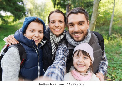 Technology, Travel, Tourism, Hike And People Concept - Happy Family With Backpacks Taking Selfie And Hiking