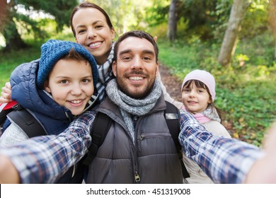 Technology, Travel, Tourism, Hike And People Concept - Happy Family With Backpacks Taking Selfie And Hiking