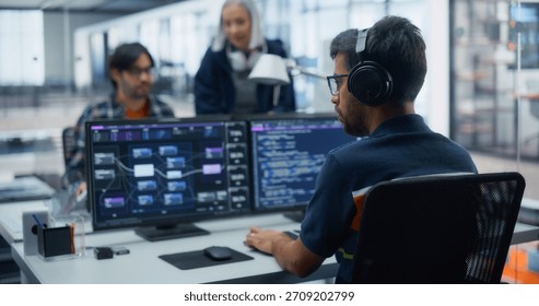 Tech-savvy Professionals Collaborating on Software Development in a Modern Office. Male Programmer Focused on Dual Monitors, Colleagues Discuss Project Strategies, Fostering Innovation and Teamwork. - Powered by Shutterstock - Get 15% off with code: PIKWIZARD15