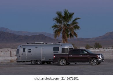 Tecopa, California, USA - March 24, 2022: image of an Airstream Trailer and pickup truck shown in the Mojave Desert at daybreak.