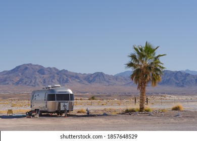 TECOPA, CALIFORNIA, USA - NOVEMBER 19, 2020: Airstream Travel Trailer and palm tree shown against a desert landscape in Inyo County.