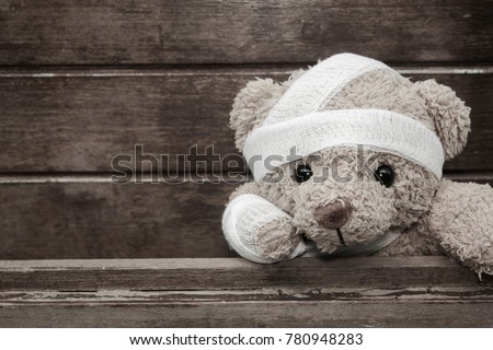 Teddy bear with bandages and broken hand on wood background in blackvand white,copy space,