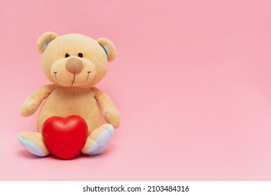 Teddy bear with big red heart isolated on pink background. Valentines day concept with copy space