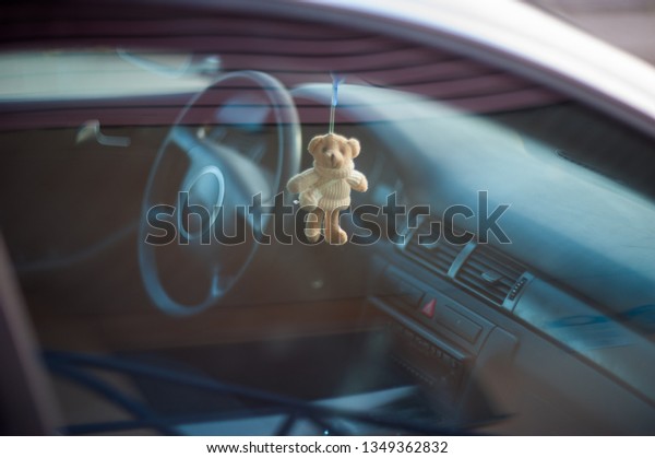 Teddy bear in the car, soft toy hanging on the\
rearview mirror