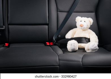 Teddy bear fastened in the back seat of a car, safety on the road - Powered by Shutterstock