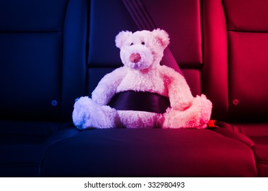 Teddy Bear Fastened In The Back Seat Of A Car, Red And Blue Police Lights