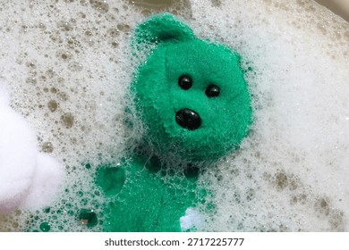 Teddy bear floating in soapy bubble water.