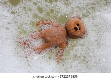 A teddy bear floating in soapy bubble water.