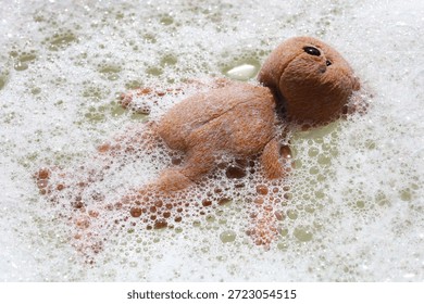 A teddy bear floating in soapy bubble water.