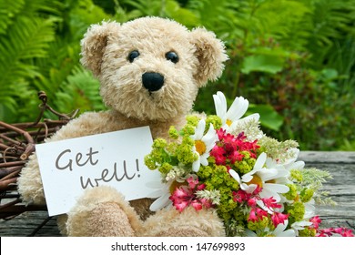 Teddybär mit Blumen und Karte mit Schriftzeichen gut/gut/tddy