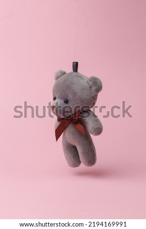 Teddy bear flying in antigravity on pink background with shadow. Levitation object in the air. Creative minimal layout