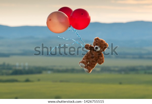 flying teddy bear with balloons