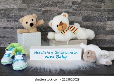 Teddy Bear And Gifts For The Baby With The Text Herzlichen Glückwunsch Zum Baby. Herzlichen Glückwunsch Zum Baby Translates To Congratulations On The Baby.