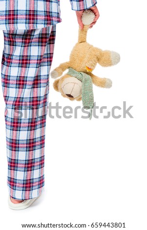 Teddy bear in the hand of a woman who goes to sleep on a white background close-up