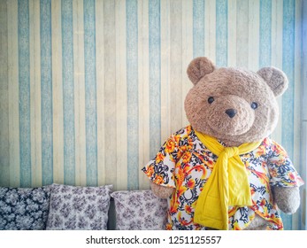 ิฺBig teddy bear in living room with pastel background patterns vintage wallpaper and cute pillow.