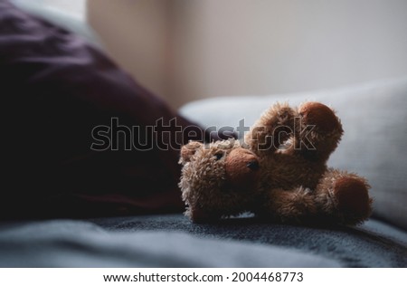 Teddy bear lying down on sofa in cinematic tone, Sad brown bear  laying alone on couch in living room with light shining from window, Lonely concept,Lost child,International missing children's day.