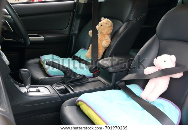Teddy bear on car front seat,\
buckled with safety belt in driving safe and white road\
concept