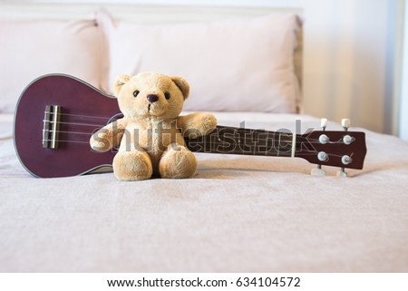 Teddy bear on comfort bed with ukulele