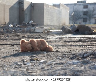 A teddy bear is on the ground of a desolate urban city with destruction for a missing child or poverty concept.
