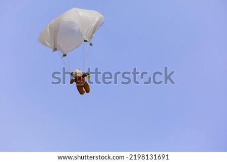 Teddy Bear on a handkerchief parachute against a blue sky, space for copy text, unusual.
